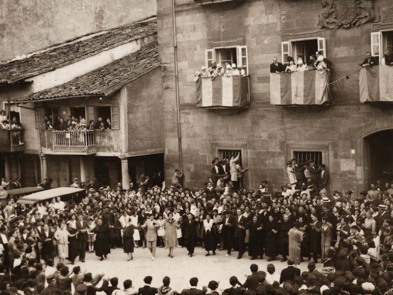 Guieldu au Repas dans la Rue d'Avilés 2024 3 Photographie ancienne d'habitants d'Avilés dansant la danza prima sur la même place, devant le palais de Ferrera et l'Hôtel de Ville d'Avilés