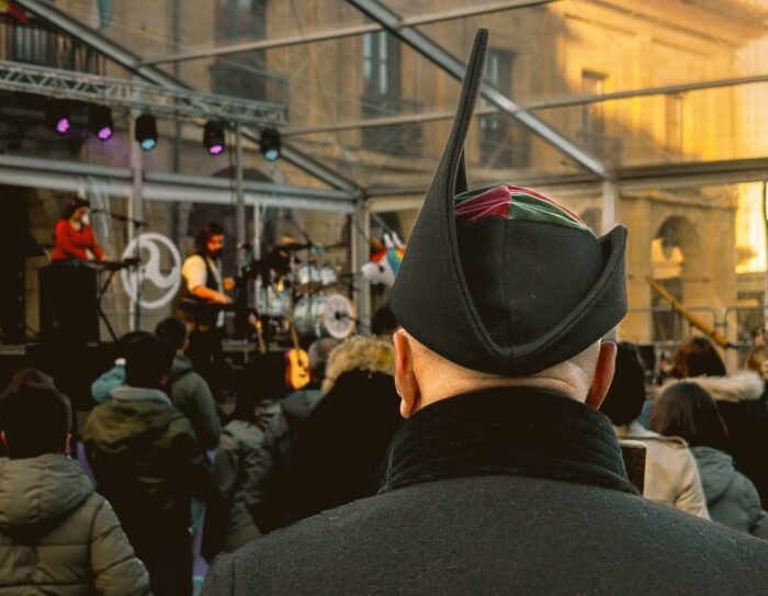 Guieldu au Repas dans la Rue d'Avilés 2024 4 Une personne du public assistant au concert de Guieldu à Avilés avec la coiffure montera picona caractéristique du costume traditionnel asturien.